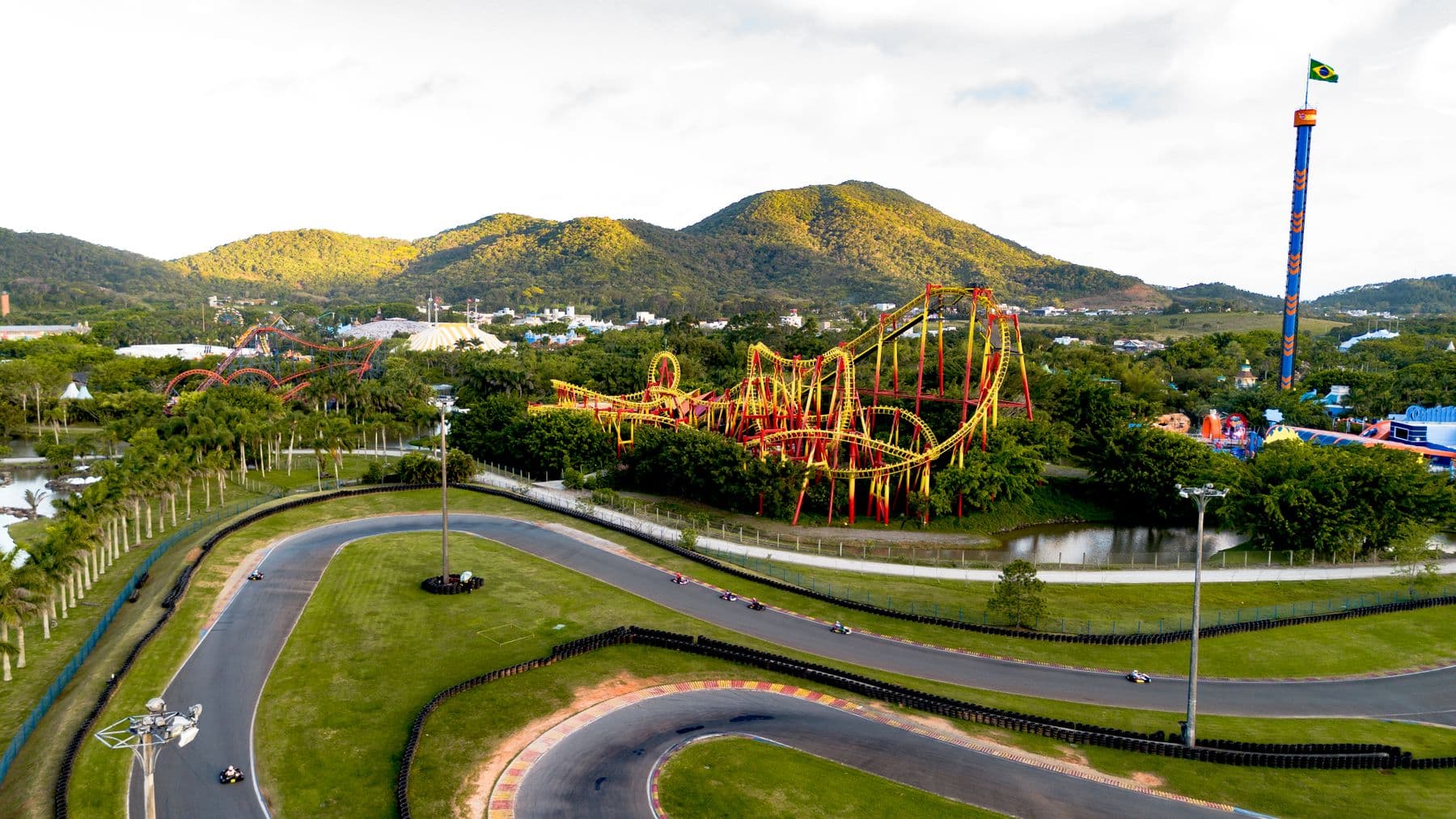 Vista aérea da pista de kart e da montanha-russa do parque em Penha, com os morros ao fundo