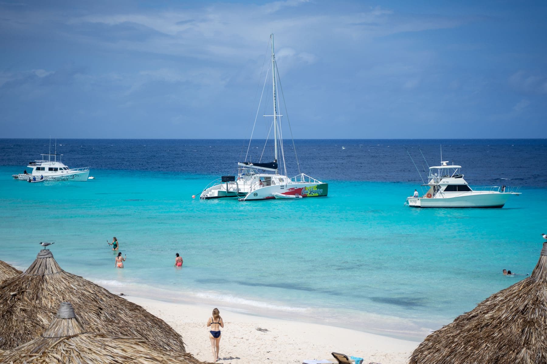 Barcos diante de praia com mar azul intenso em Curaçao