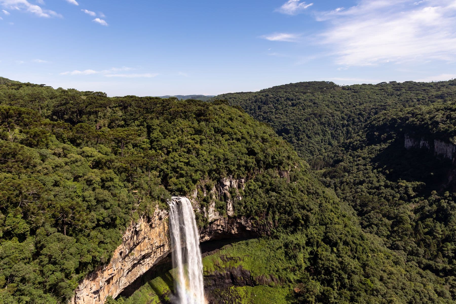 Vista aérea da Cascata do Caracol cercada de floresta verde, em Gramado