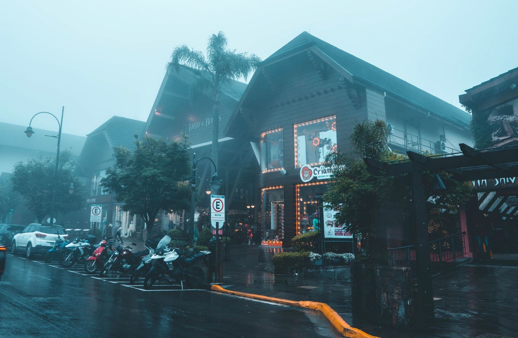 Rua de Gramado em dia de neblina, com arquitetura de chalés e vitrines iluminadas