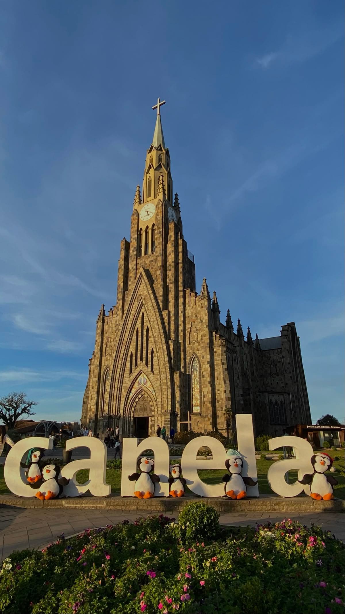 Catedral de Pedra de Canela diante do letreiro da cidade e de um jardim florido