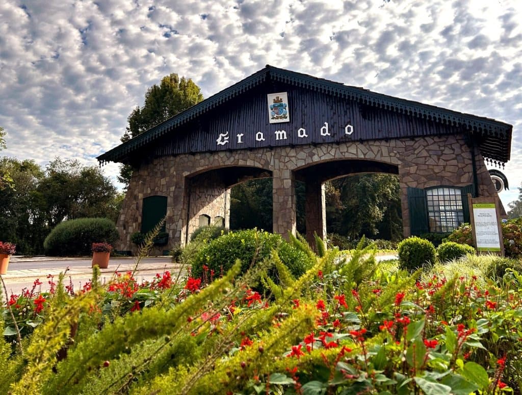 Pórtico de entrada de Gramado cercado por jardins floridos