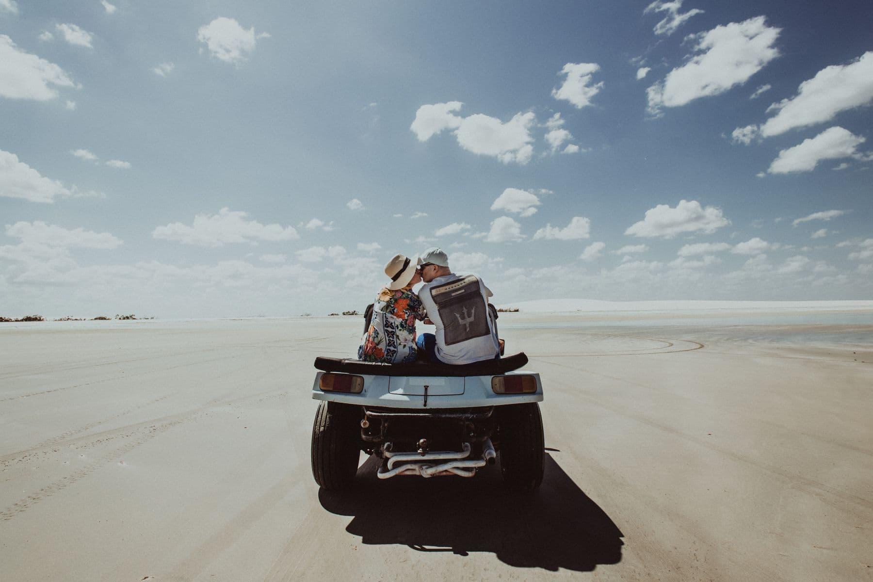 Casal em um buggy azul atravessando a areia batida em Jericoacoara, no Ceará