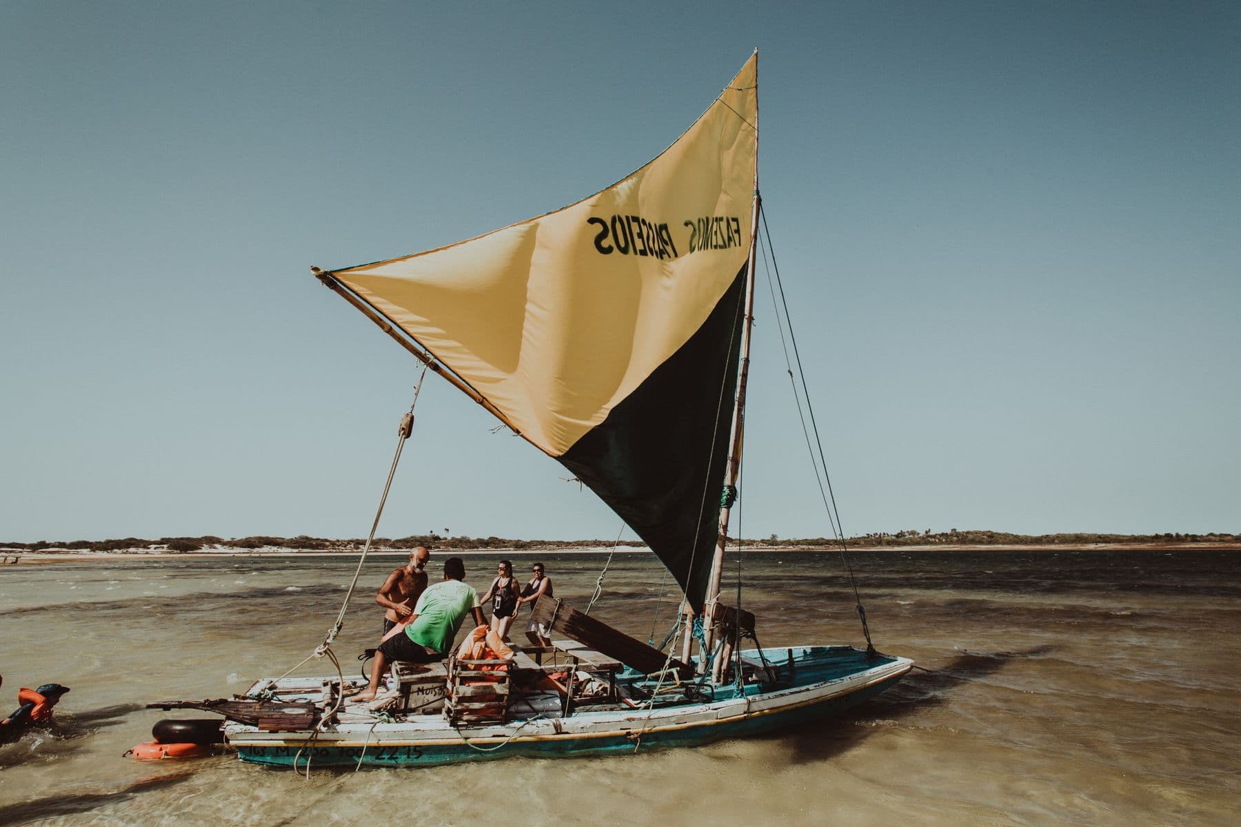 Jangada de vela amarela navegando na água rasa em Jericoacoara, no Ceará