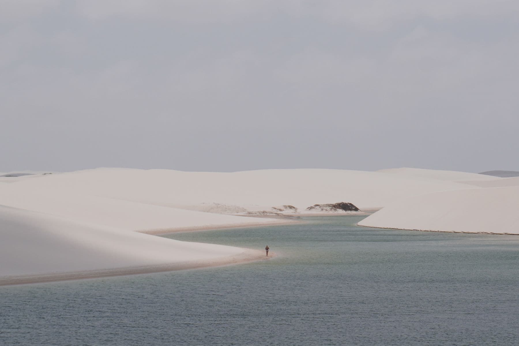 Pessoa sozinha caminhando na faixa de areia entre lagoas, em Atins, nos Lençóis Maranhenses