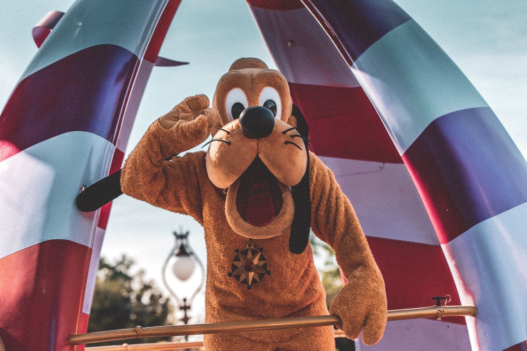 Pluto acenando durante um desfile ensolarado em parque de Orlando
