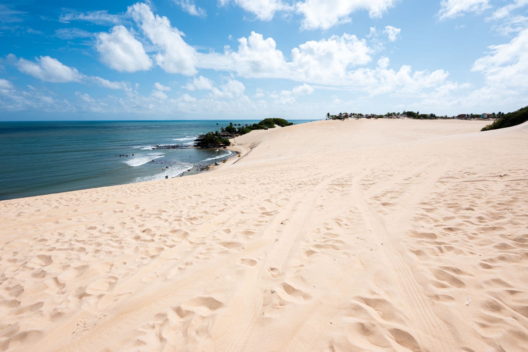 Duna larga descendo até o mar no litoral de Natal, sob céu azul